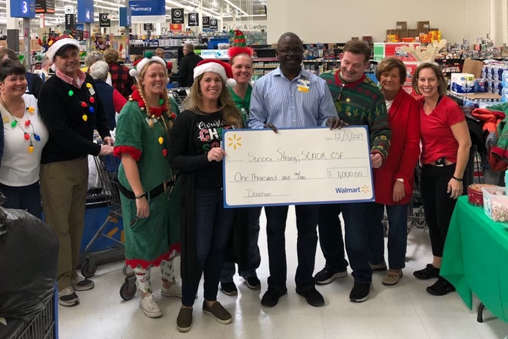 About Sussex Strong Women holding a check for $500